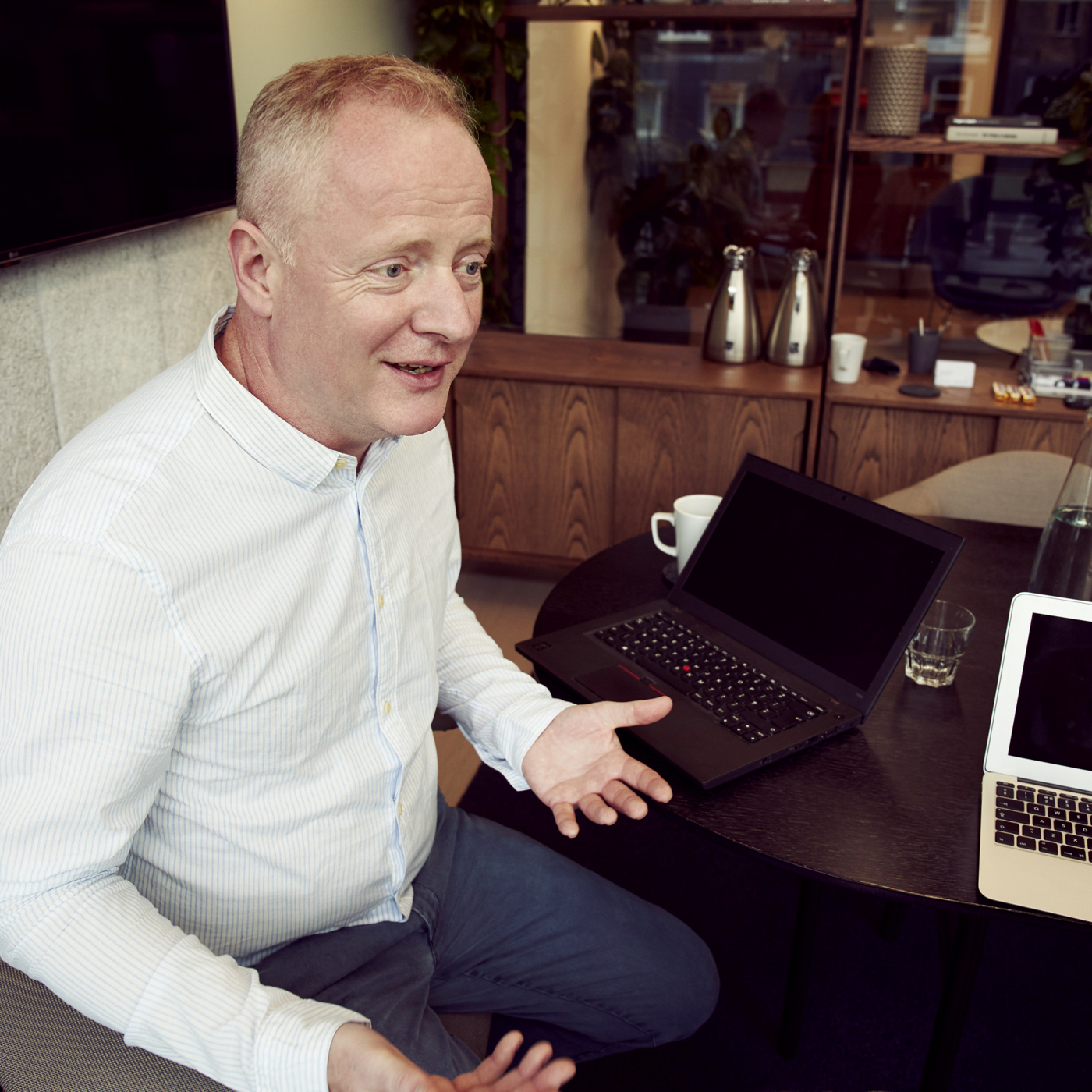 man-wearing-long-sleeved-shirt-sitting-beside-table-2977544